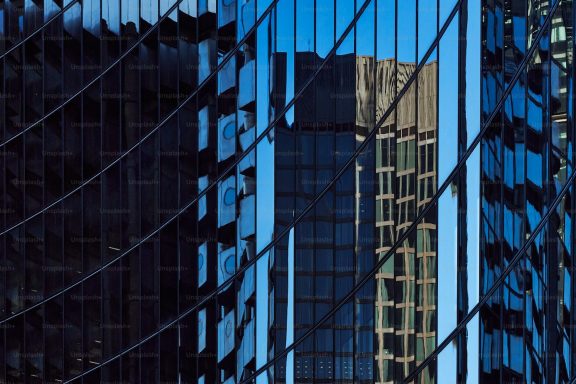 Reflets de bâtiments modernes sur une façade en verre.