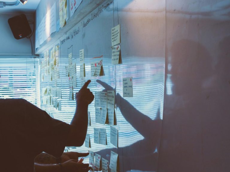 Conseils stratégiques Person montrant des notes autocollantes sur un tableau dans un environnement de travail.