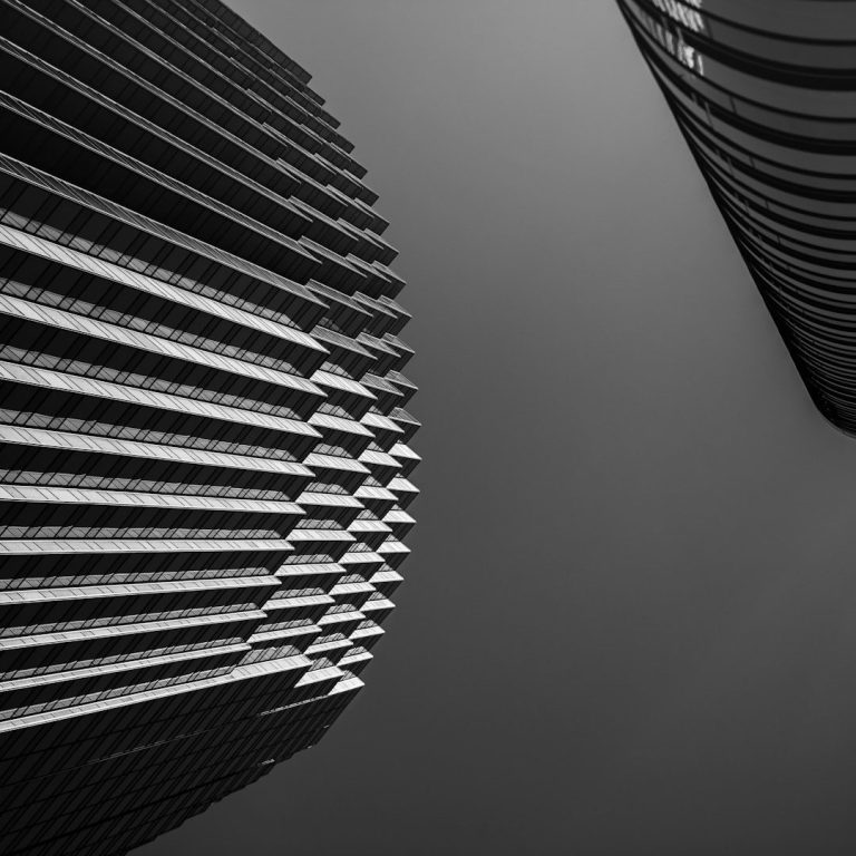 Riviera Détective Divorce Vue en contre-plongée de deux gratte-ciel en noir et blanc, avec des lignes géométriques.