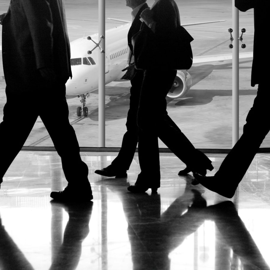 RivierX intelligence international Des silhouettes de voyageurs marchant vers un avion à l'aéroport.