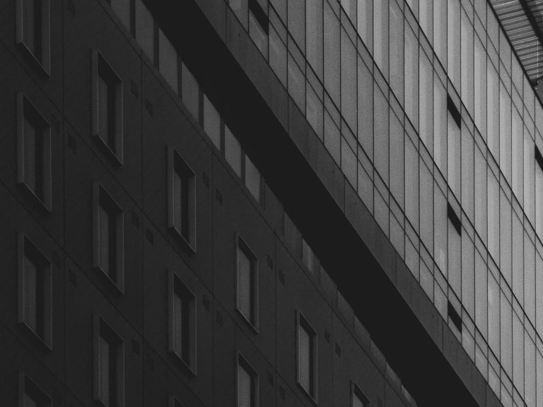 Détective privé menant une filature – RivierX Façade d'un immeuble moderne, avec des fenêtres et des lignes géométriques.
