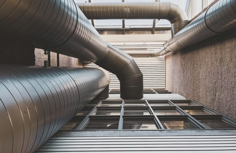 HVAC RivierX Vue en contre-plongée de tuyaux en métal dans un environnement urbain.